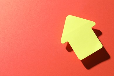 Photo of One yellow paper arrow on red background, top view. Space for text