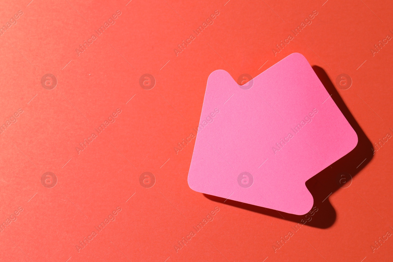 Photo of One pink paper arrow on red background, top view. Space for text