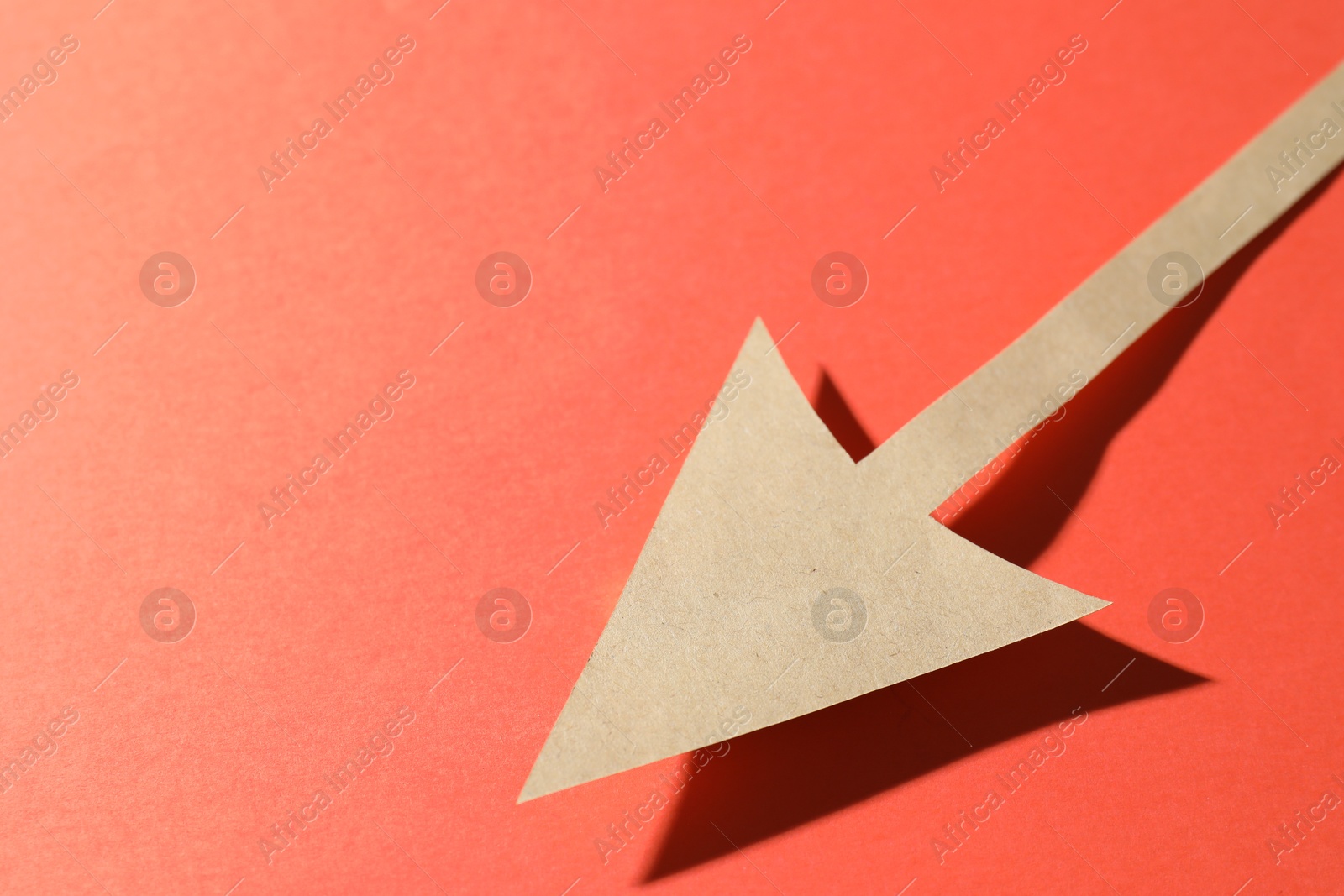 Photo of One kraft paper arrow on red background, closeup. Space for text