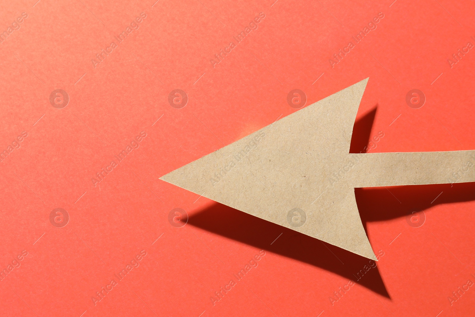 Photo of One kraft paper arrow on red background, top view. Space for text