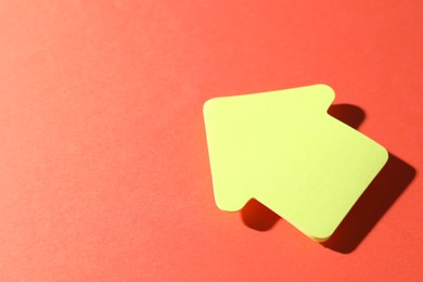 Photo of One yellow paper arrow on red background, space for text