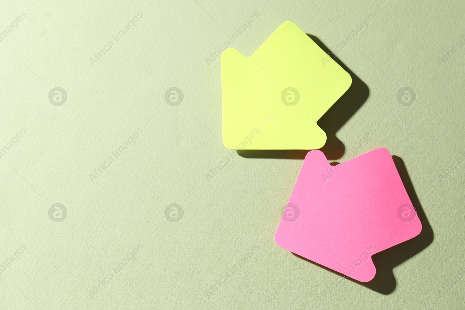 Photo of Colorful paper arrows on light green background, flat lay. Space for text