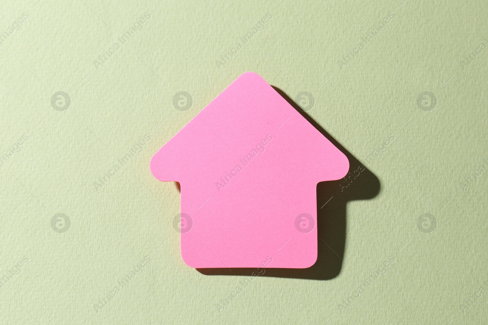 Photo of One pink paper arrow on light green background, top view