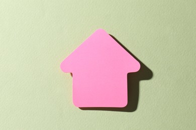 Photo of One pink paper arrow on light green background, top view