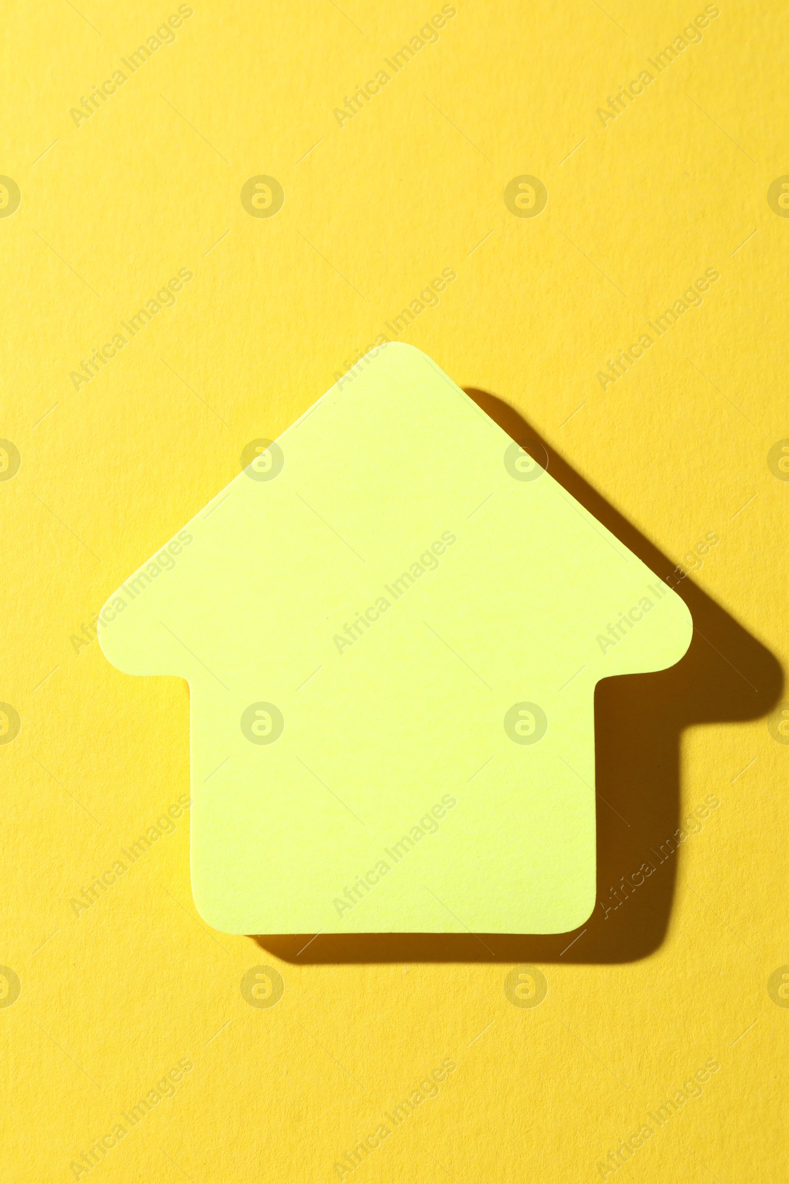 Photo of One paper arrow on yellow background, top view