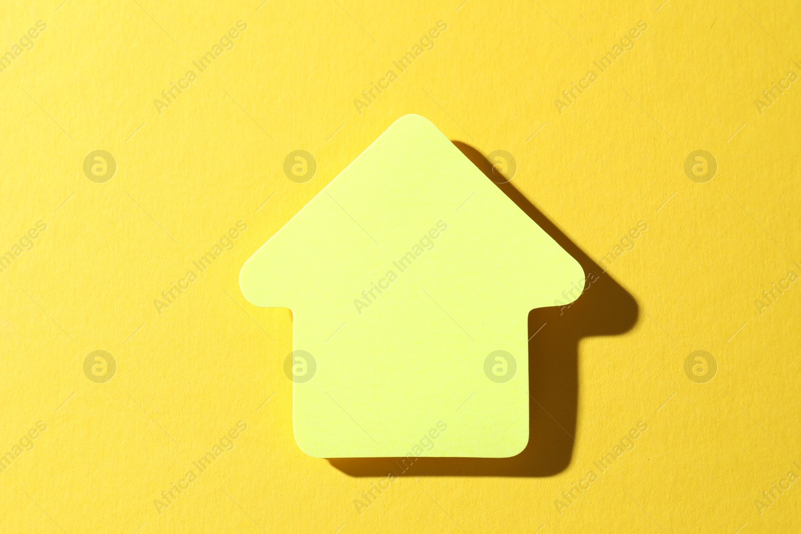 Photo of One paper arrow on yellow background, top view