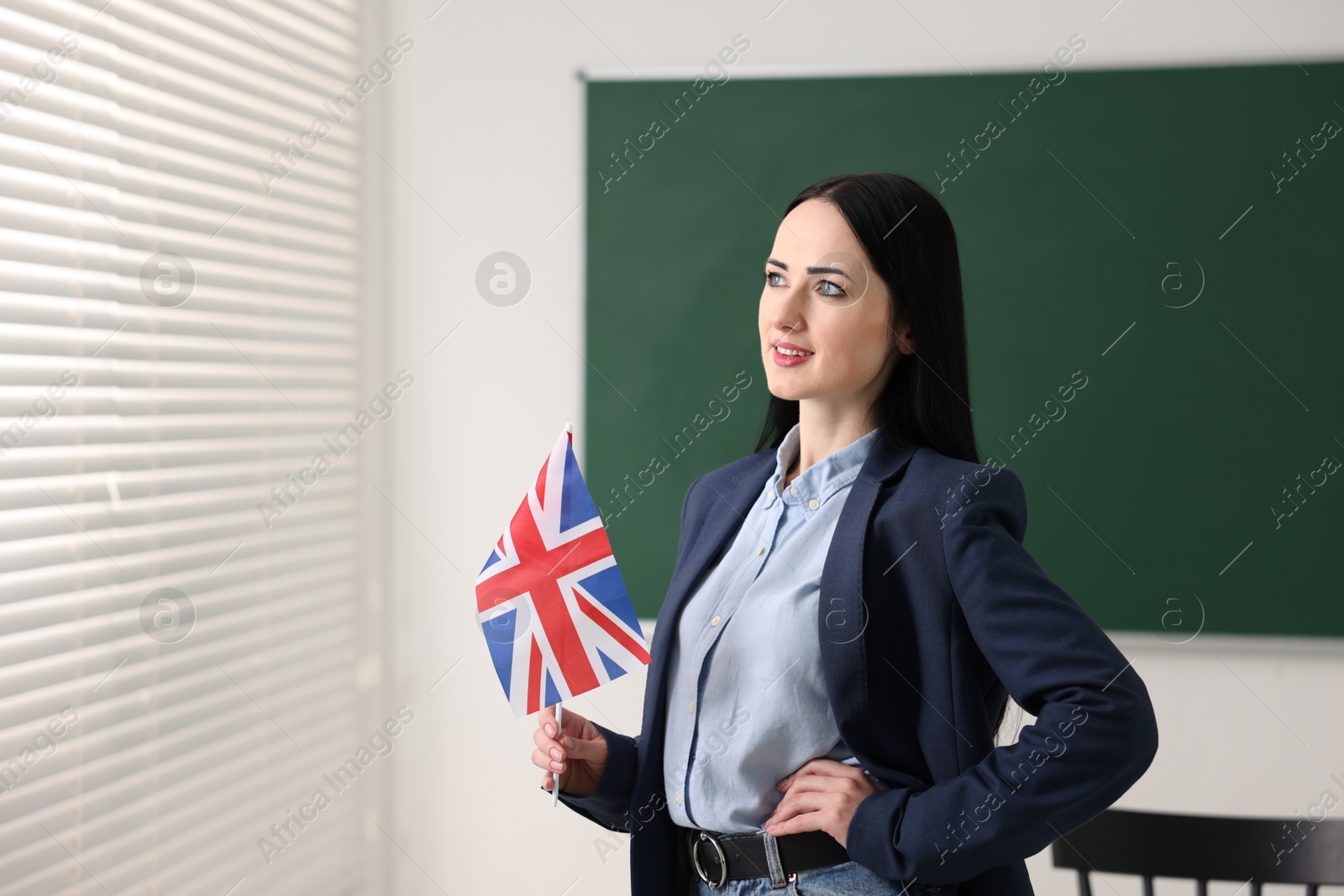 Photo of English teacher with UK flag in classroom. Space for text