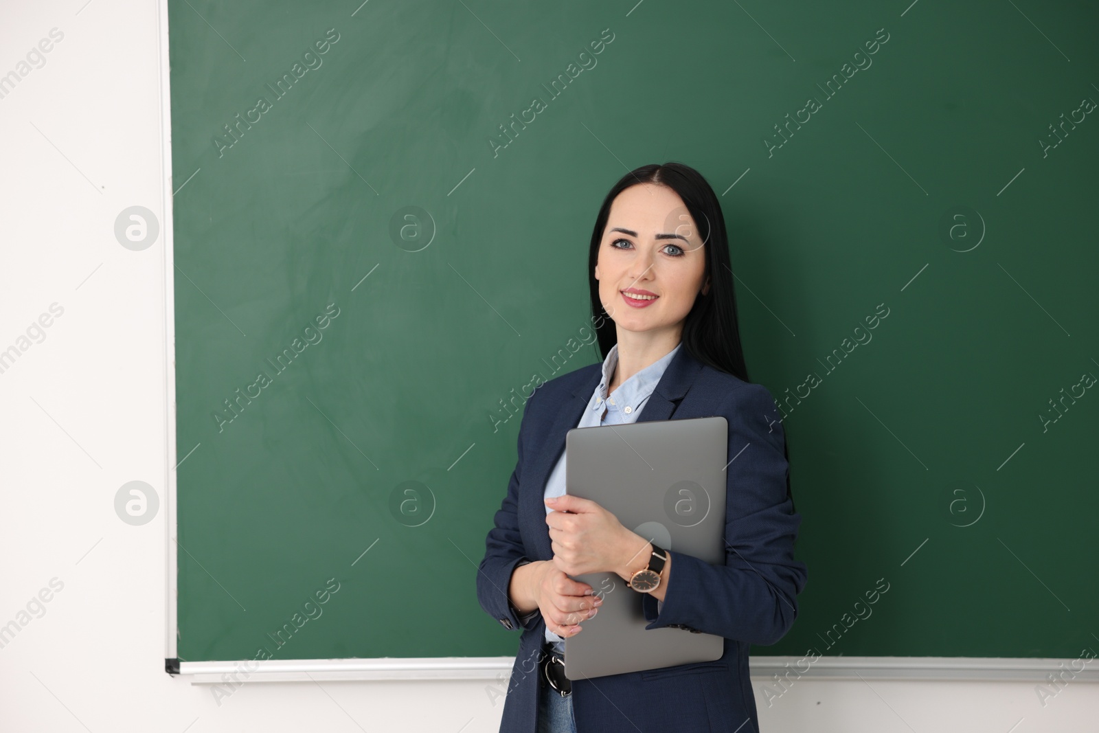 Photo of English teacher with laptop near chalkboard in classroom