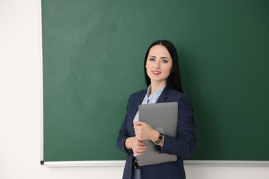 Photo of English teacher with laptop near chalkboard in classroom