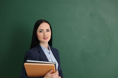 Photo of English teacher with books near chalkboard in classroom. Space for text