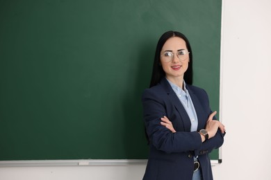 Photo of English teacher near chalkboard in classroom. Space for text