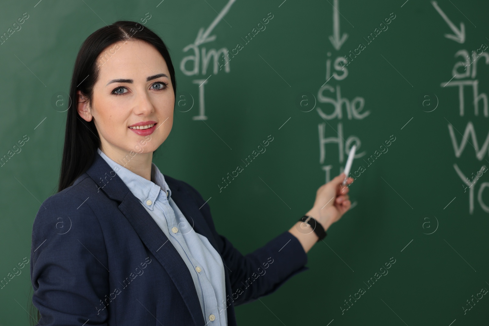 Photo of English teacher during lesson near chalkboard in classroom