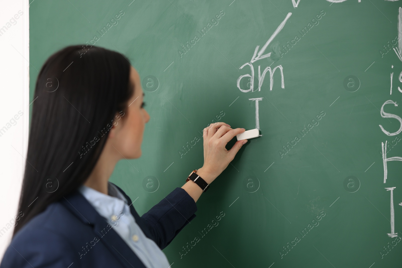 Photo of English teacher during lesson near chalkboard in classroom