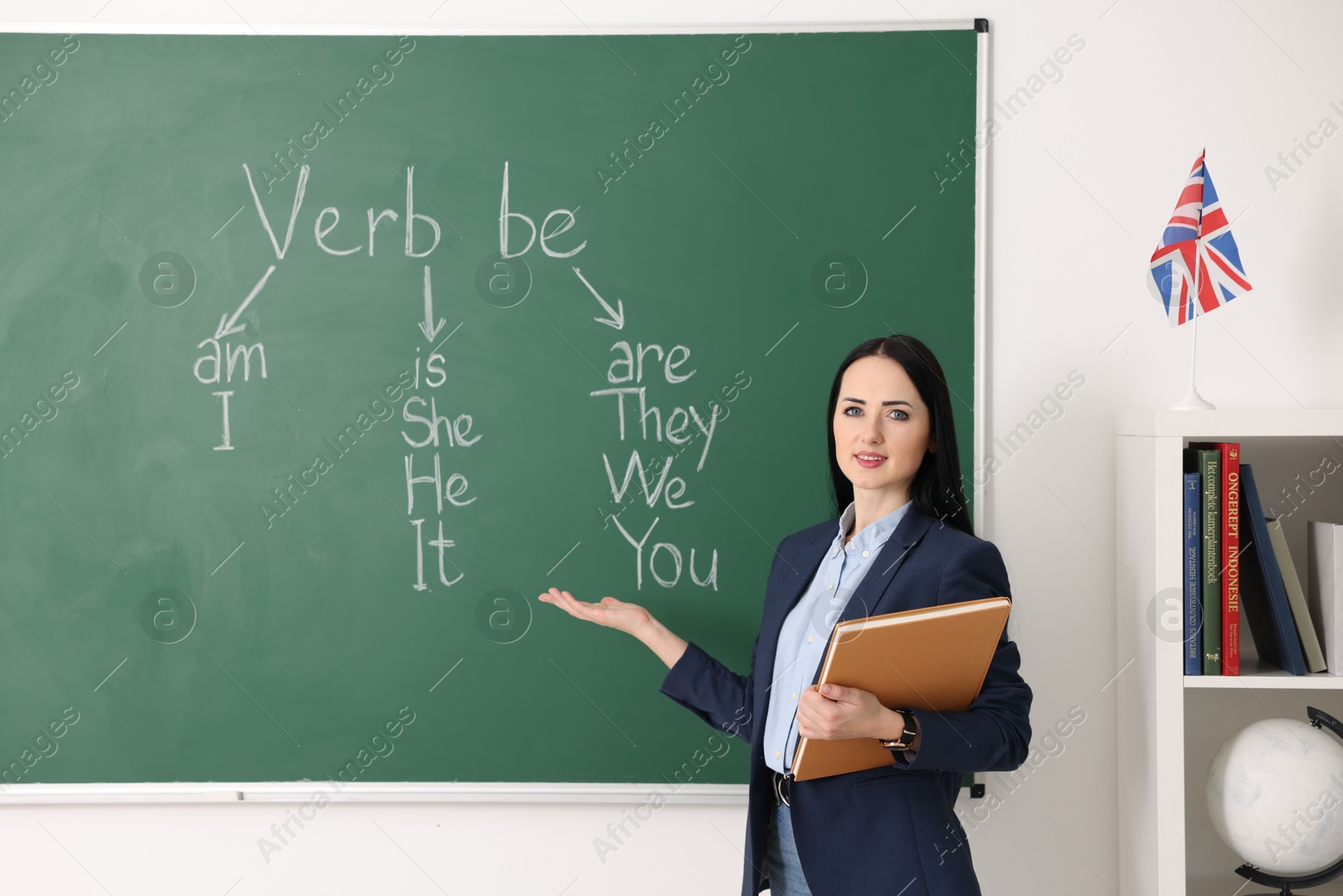 Photo of English teacher during lesson near chalkboard in classroom