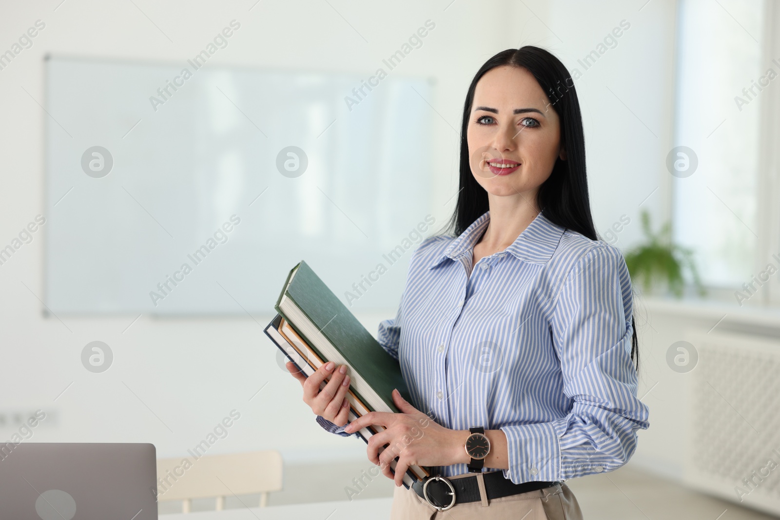 Photo of English teacher with books in classroom. Space for text