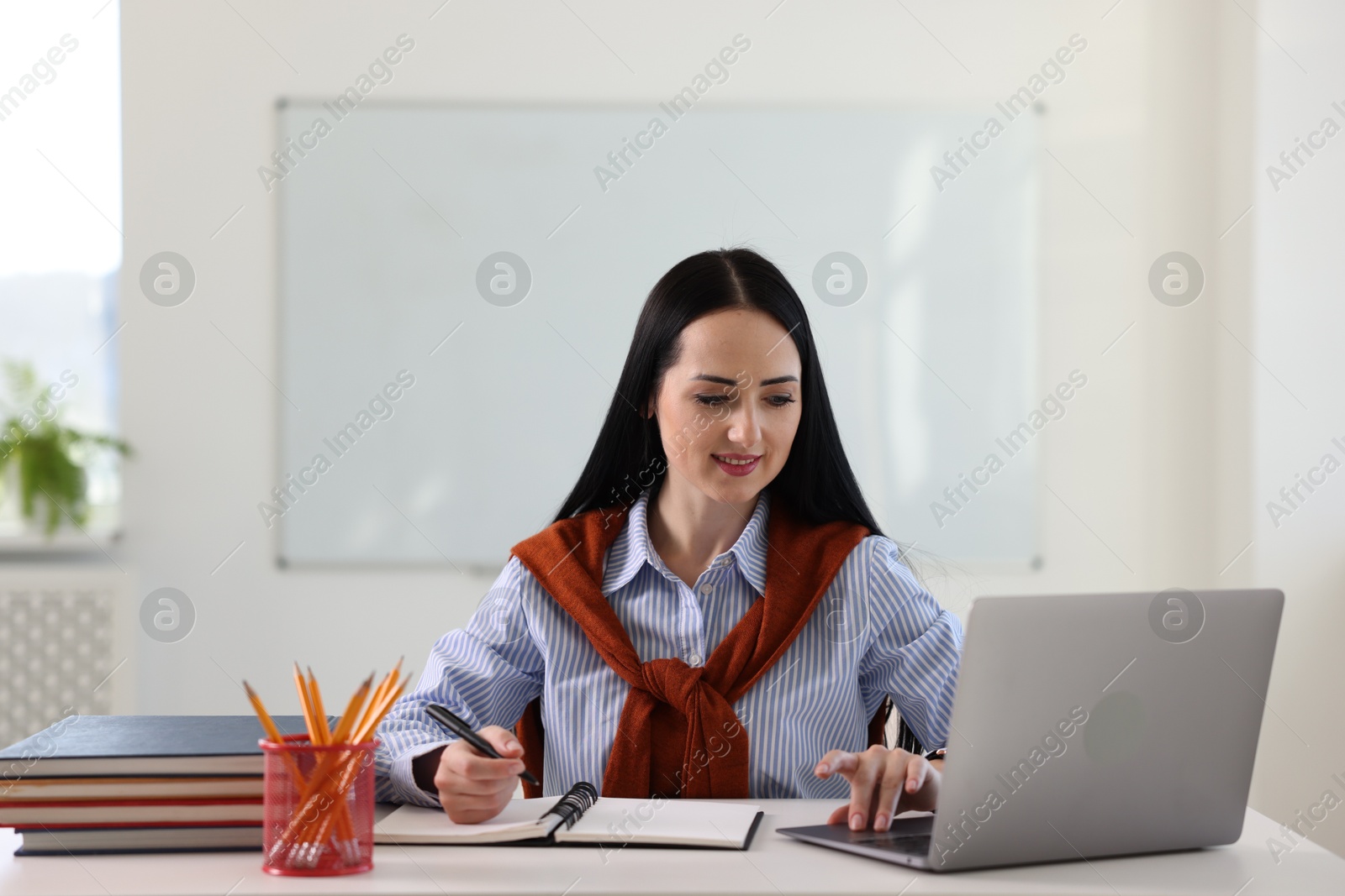 Photo of English teacher working at desk in classroom