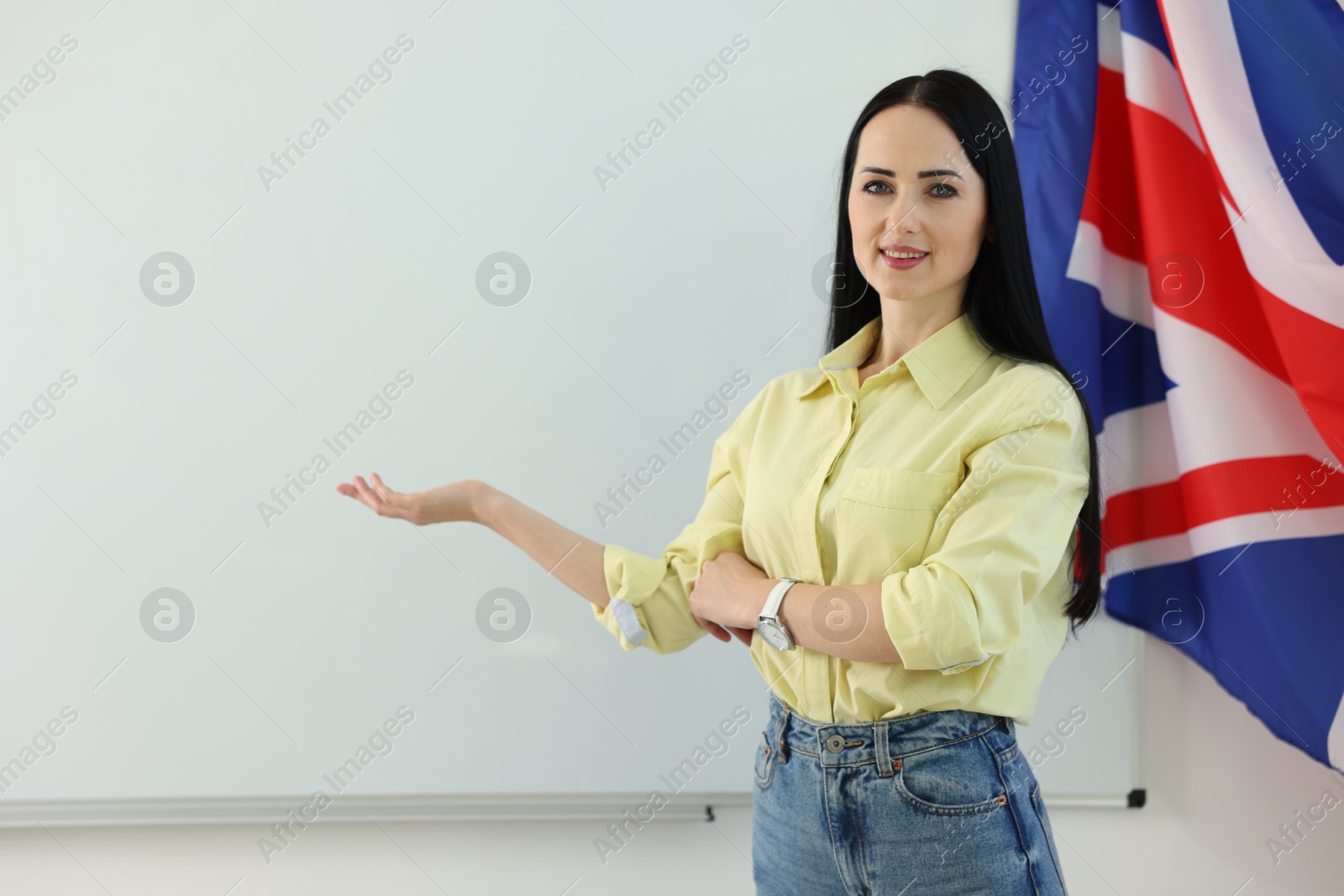 Photo of English teacher explaining something near whiteboard in classroom. Space for text