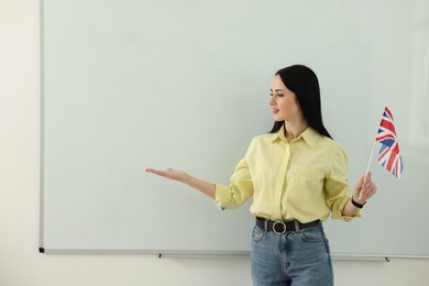 Photo of English teacher explaining something near whiteboard in classroom. Space for text