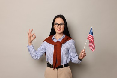 Photo of English teacher with American flag showing ok gesture on light grey background