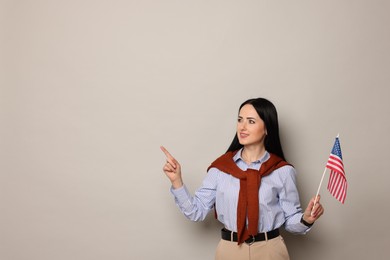 Photo of English teacher with American flag pointing at something on light grey background. Space for text