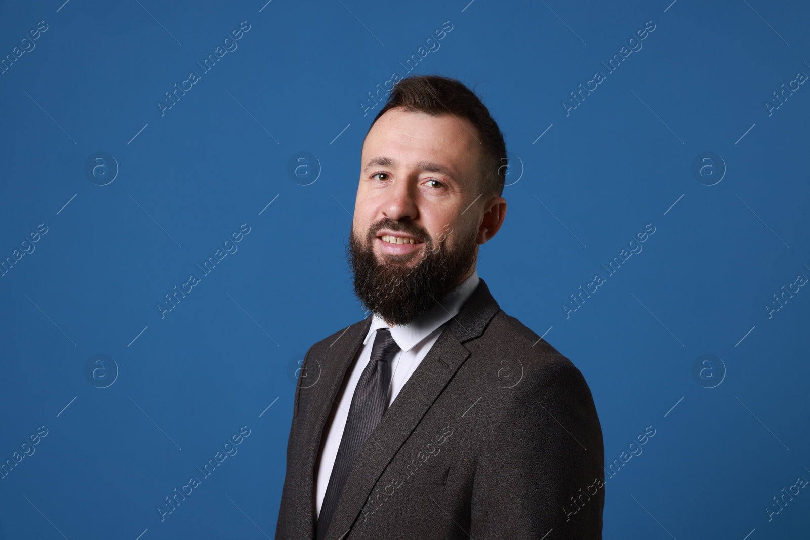 Photo of Handsome bearded man in suit on blue background