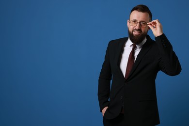 Handsome bearded man in suit on blue background. Space for text