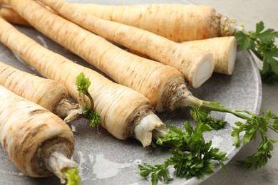 Photo of Whole and cut fresh parsley roots on table, closeup