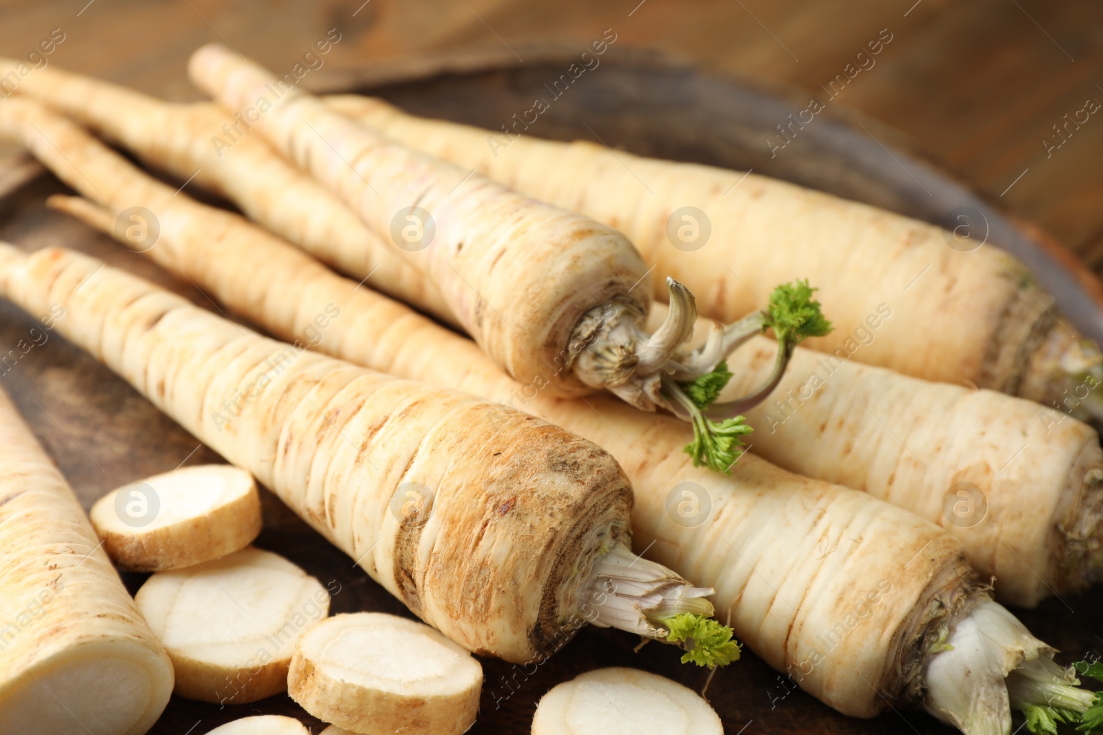 Photo of Whole and cut fresh parsley roots on table, closeup