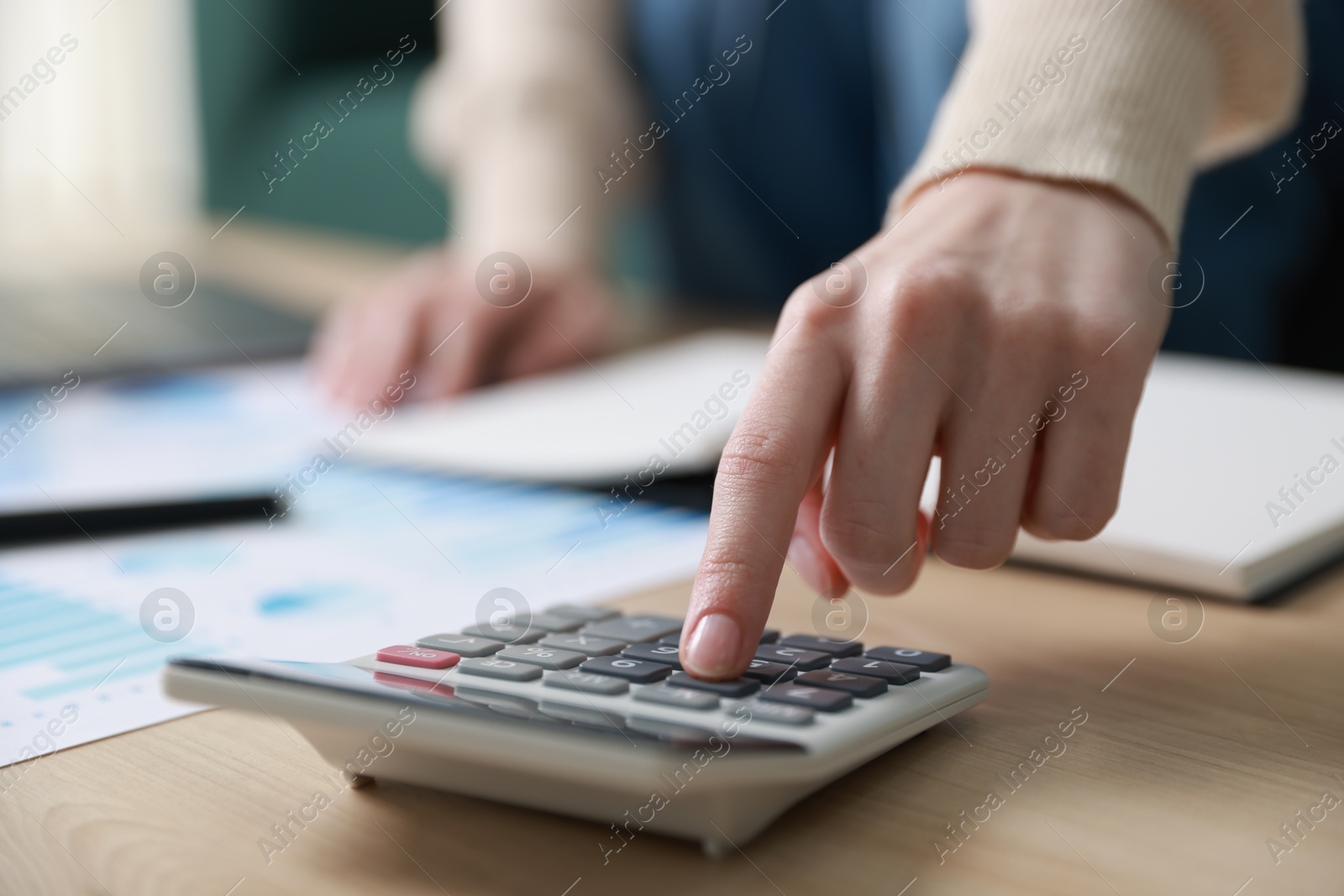 Photo of Budget. Woman with paperwork and calculator at wooden desk indoors, closeup