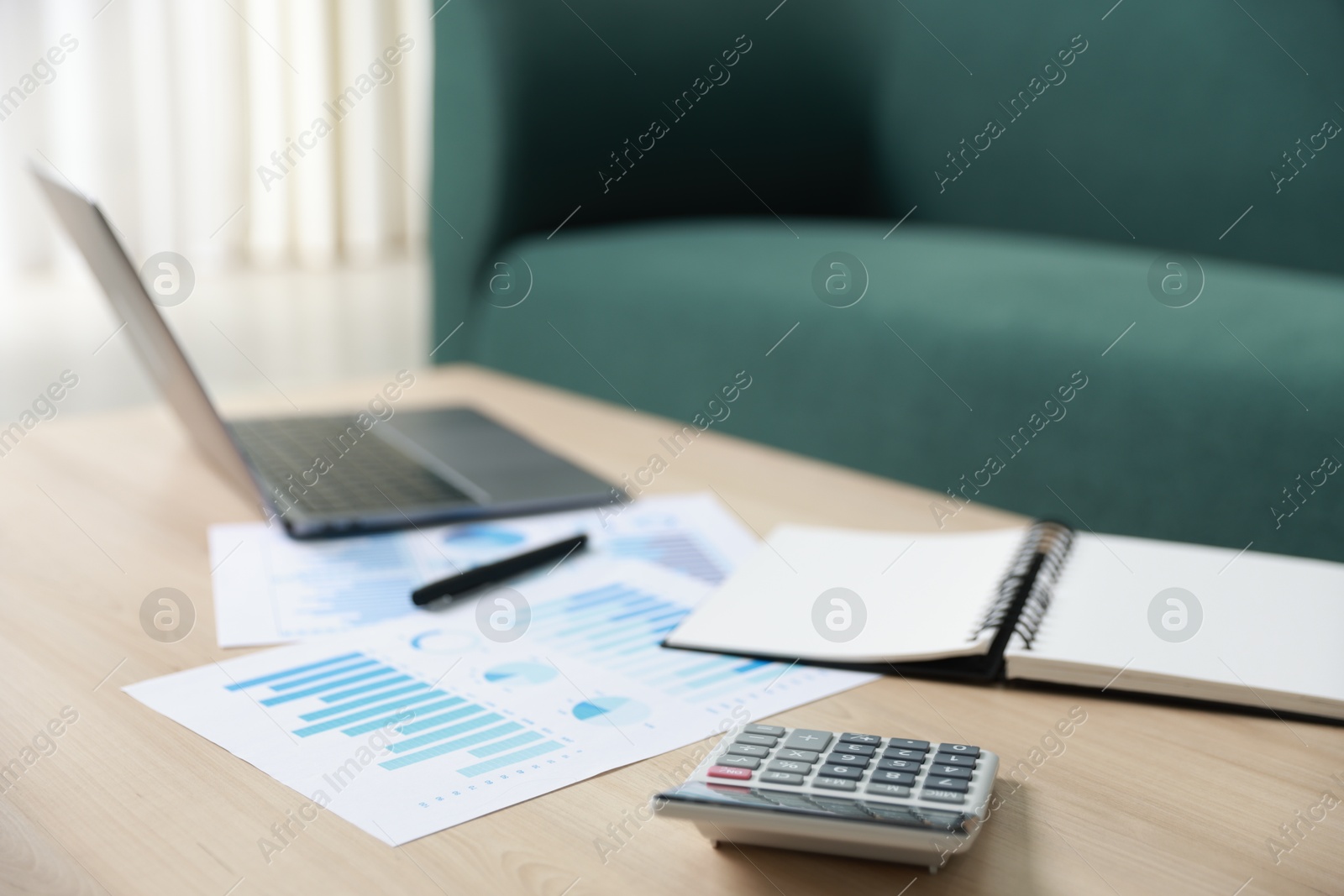 Photo of Budget. Calculator, paperwork and laptop on wooden desk indoors