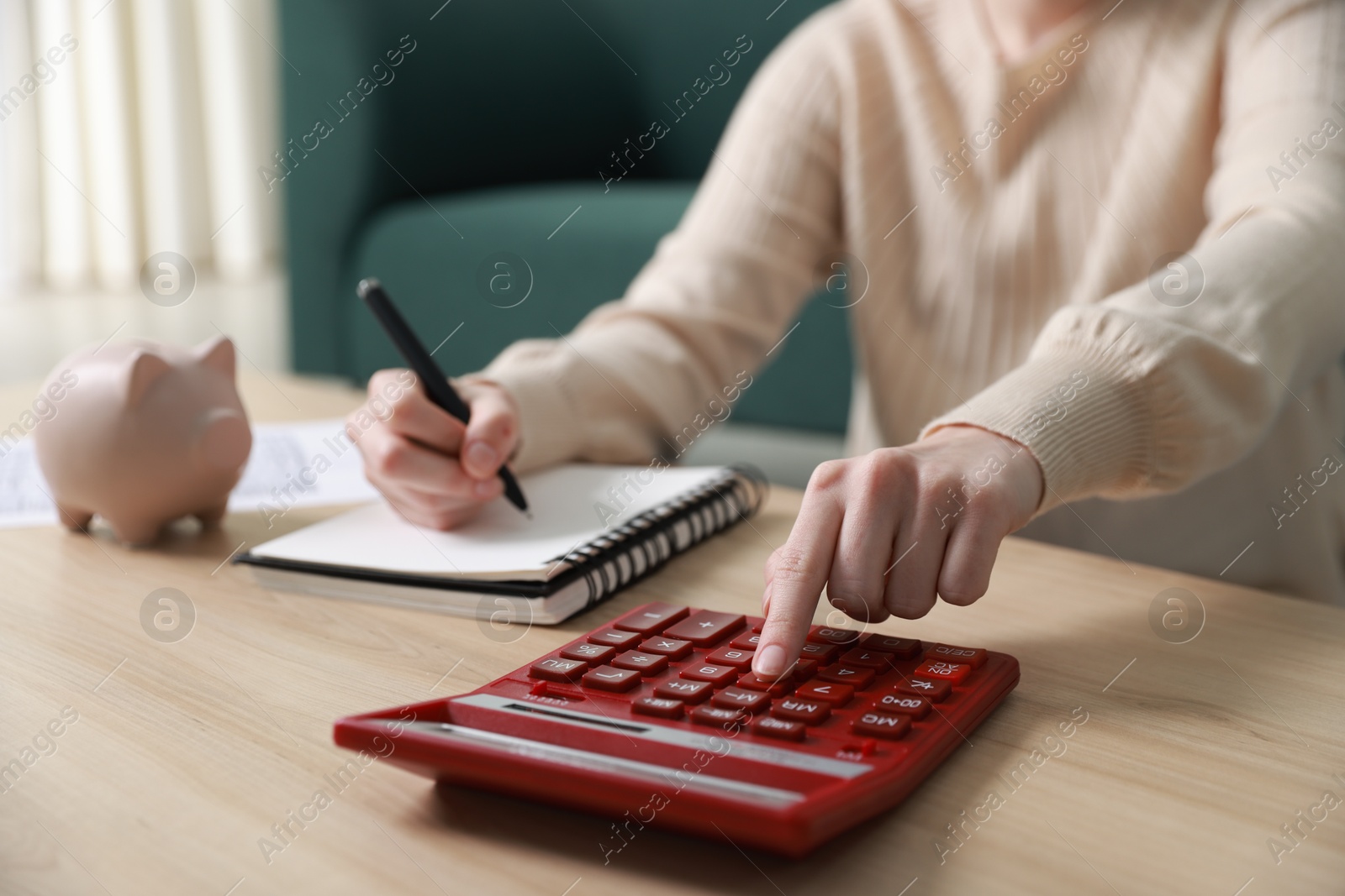 Photo of Budget. Woman with paperwork and calculator at wooden desk indoors, closeup