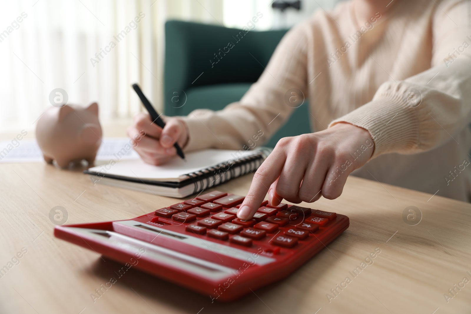 Photo of Budget. Woman with paperwork and calculator at wooden desk indoors, closeup