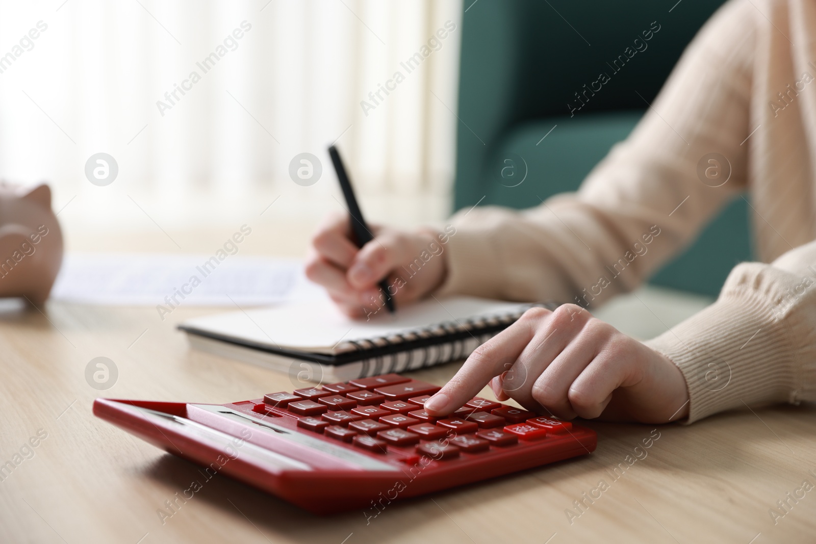 Photo of Budget. Woman with paperwork and calculator at wooden desk indoors, closeup