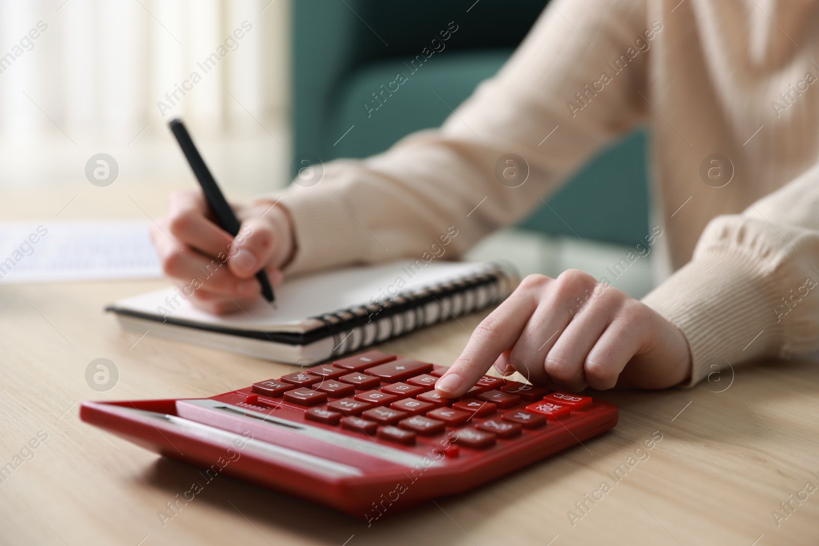 Photo of Budget. Woman with paperwork and calculator at wooden desk indoors, closeup