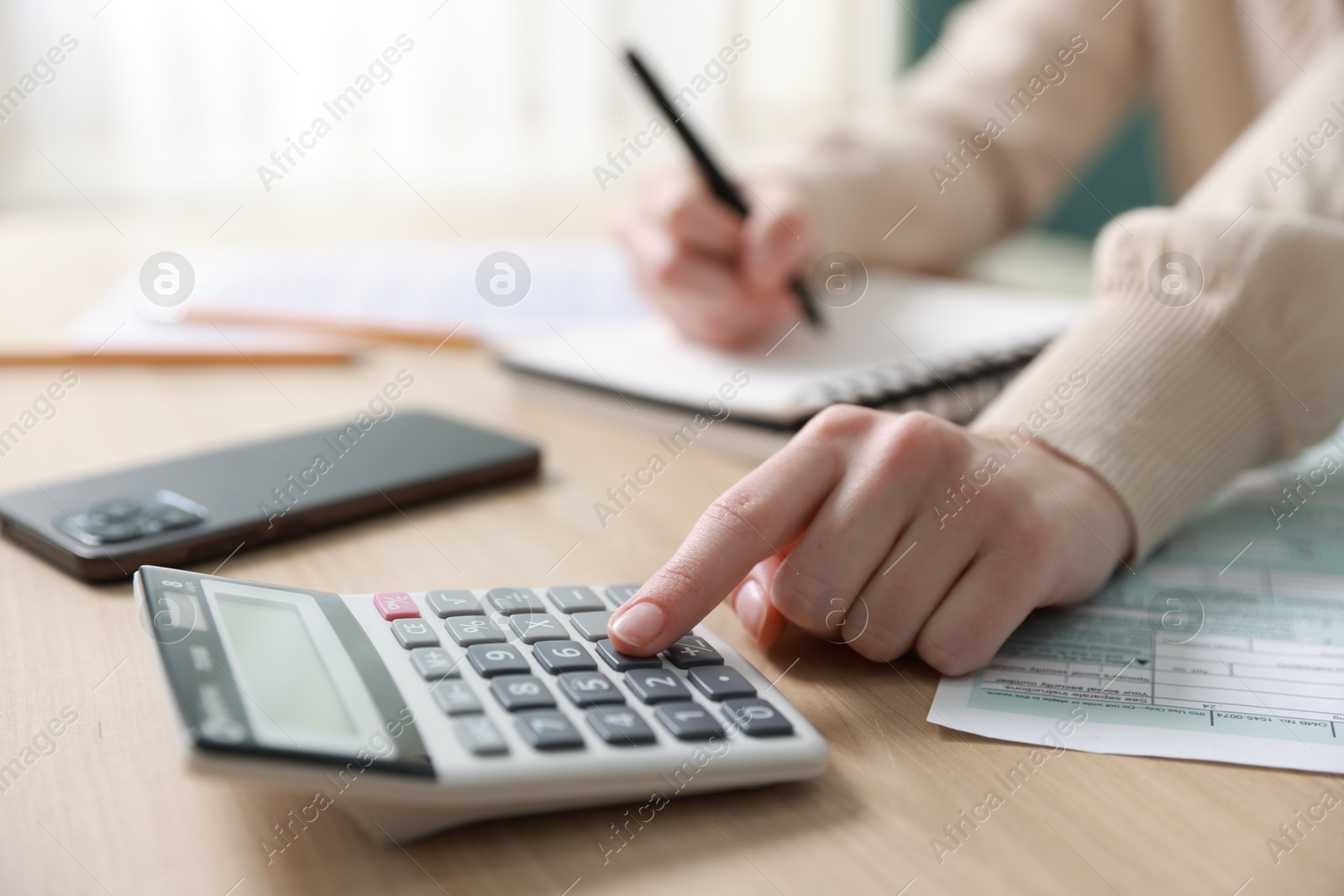 Photo of Budget. Woman with paperwork and calculator at wooden desk indoors, closeup