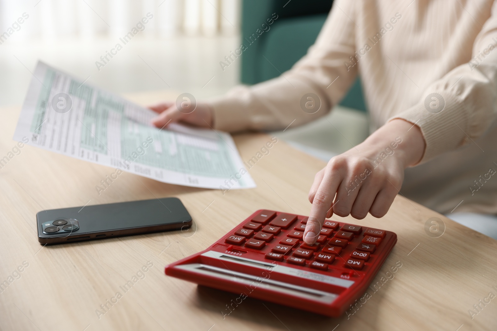 Photo of Budget. Woman with paperwork and calculator at wooden desk indoors, closeup