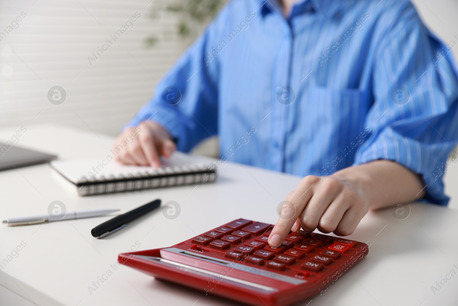 Photo of Budget. Woman with paperwork and calculator at white desk indoors, closeup