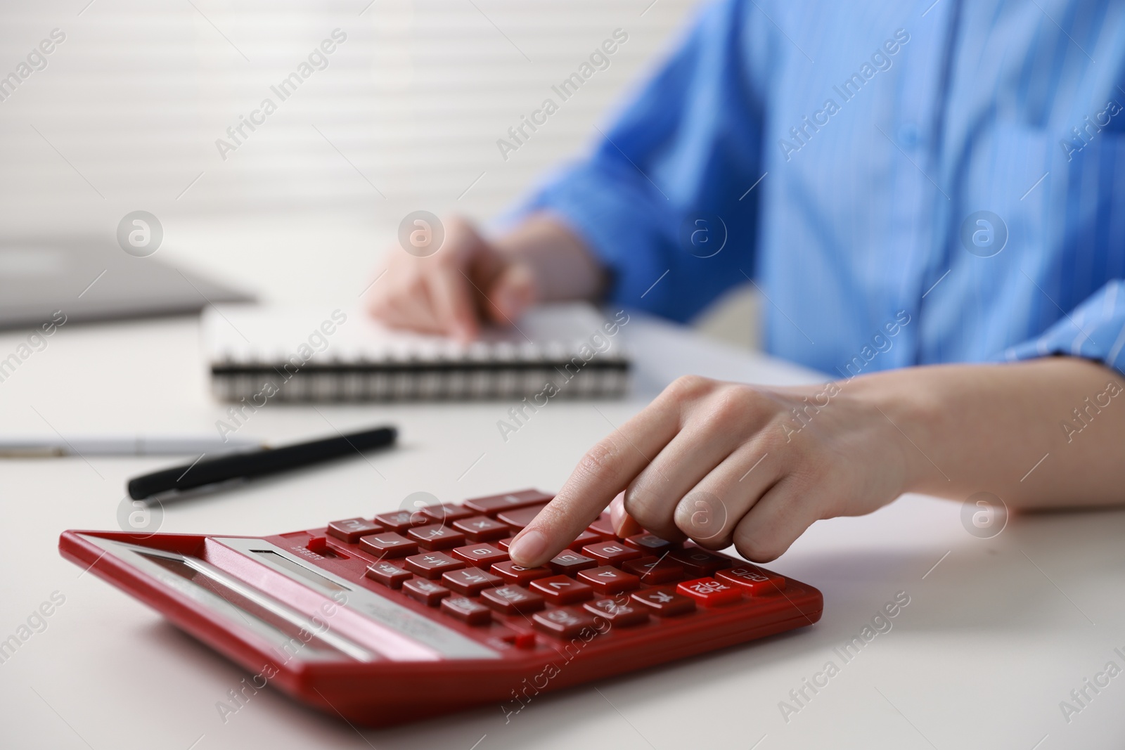 Photo of Budget. Woman with paperwork and calculator at white desk indoors, closeup