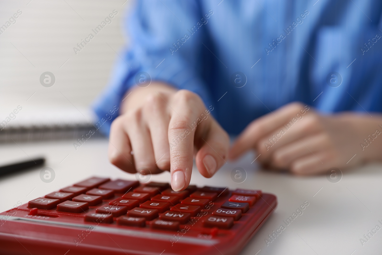 Photo of Budget. Woman with paperwork and calculator at white desk indoors, closeup