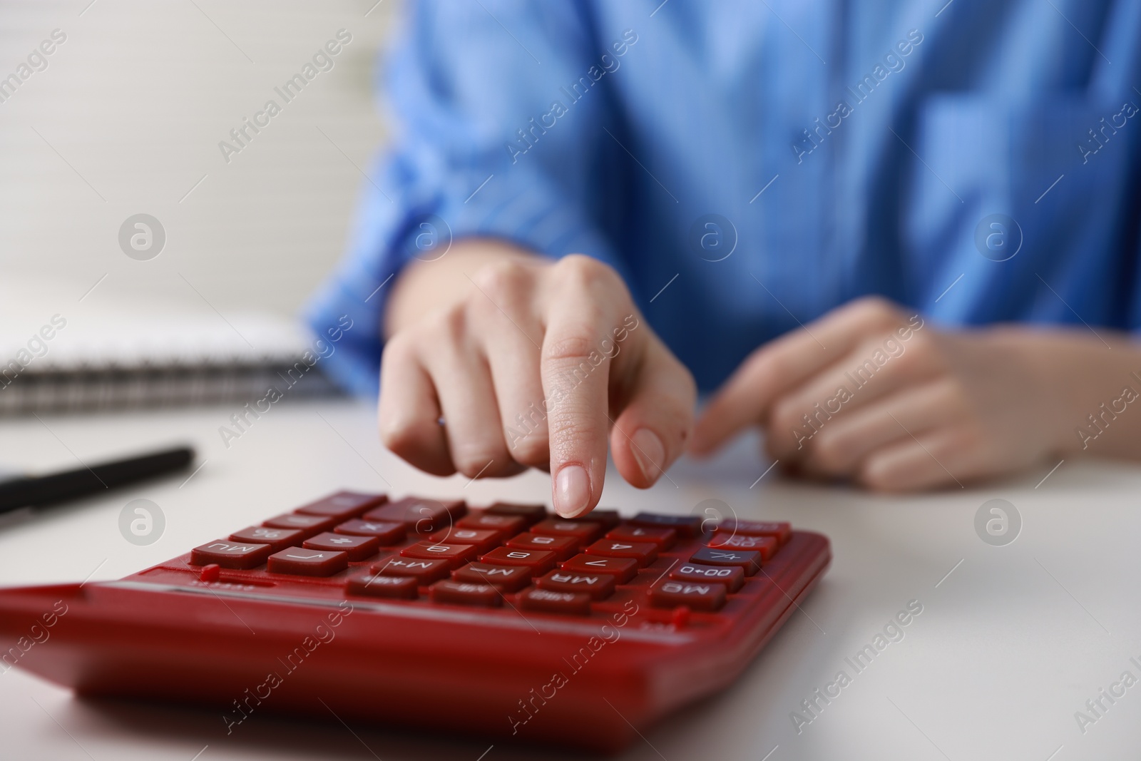 Photo of Budget. Woman with paperwork and calculator at white desk indoors, closeup