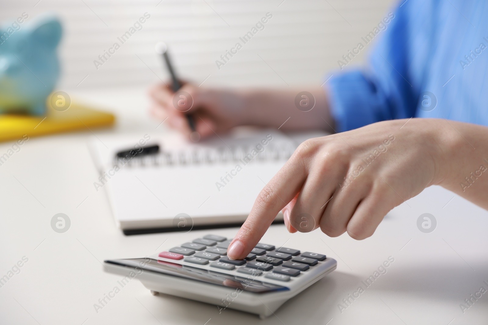 Photo of Budget. Woman with paperwork and calculator at white desk indoors, closeup