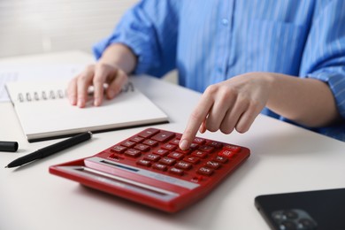 Photo of Budget. Woman with paperwork and calculator at white desk indoors, closeup