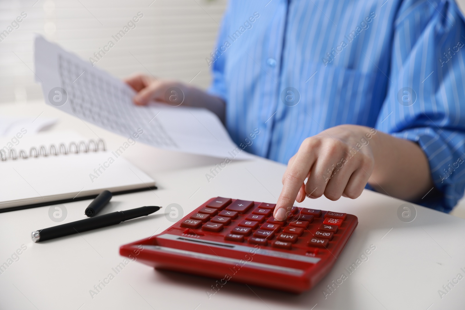 Photo of Budget. Woman with paperwork and calculator at white desk indoors, closeup