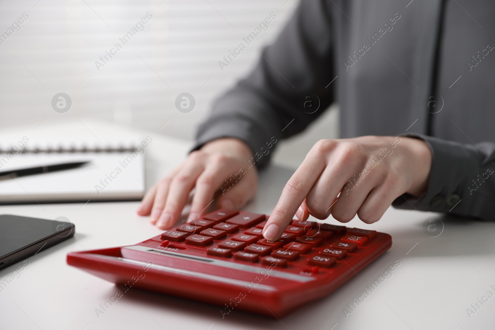 Photo of Budget. Woman with paperwork and calculator at white desk indoors, closeup