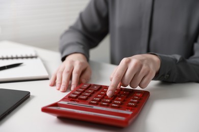 Photo of Budget. Woman with paperwork and calculator at white desk indoors, closeup