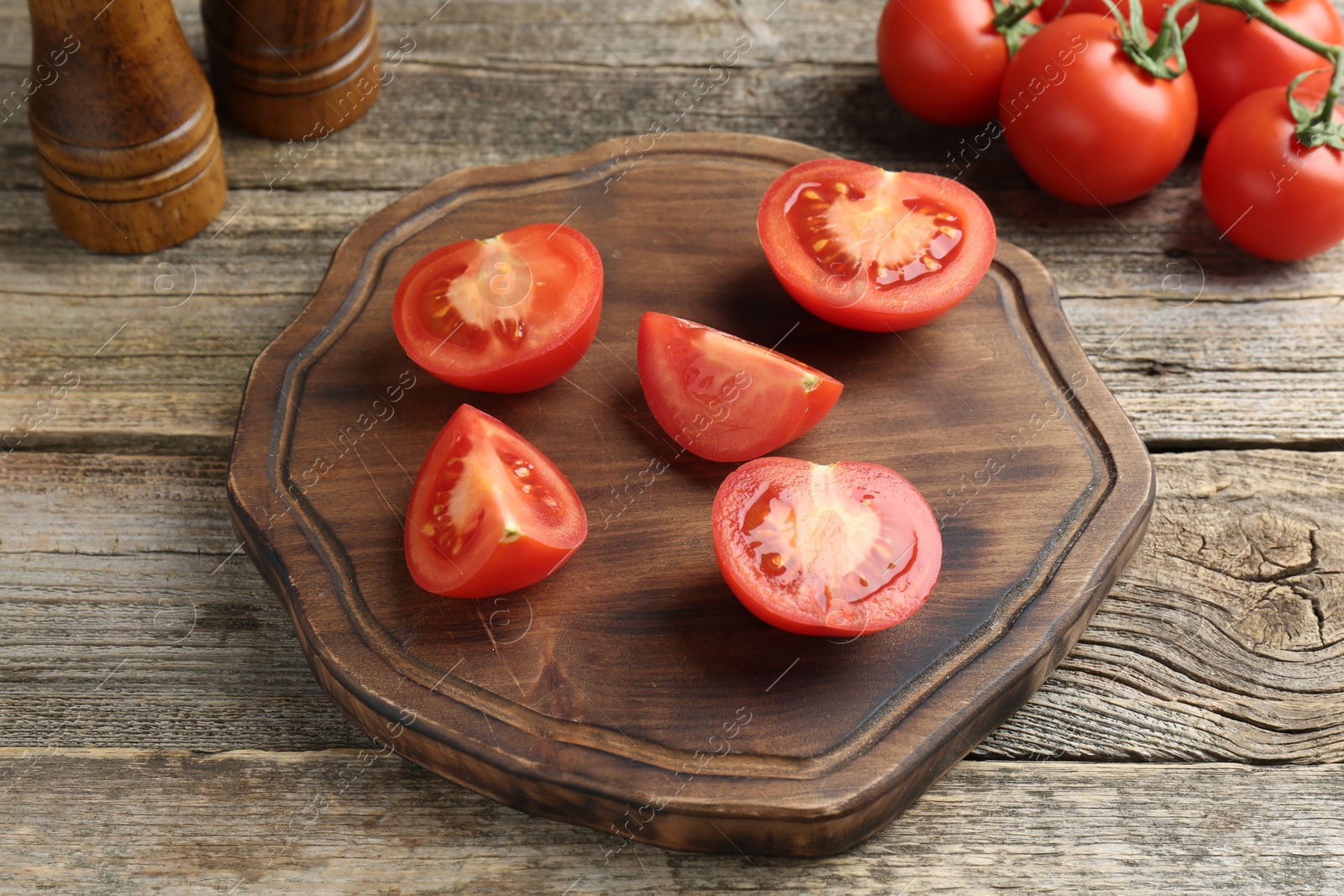 Photo of Cutting board with tomatoes on wooden table, closeup