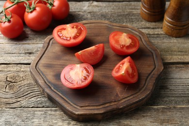 Photo of Cutting board with tomatoes on wooden table, closeup