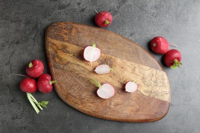 Photo of Cutting board with radishes on grey table, flat lay