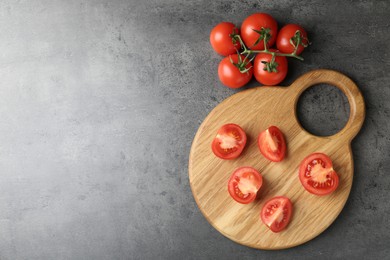 Photo of Cutting board with tomatoes on grey table, top view. Space for text