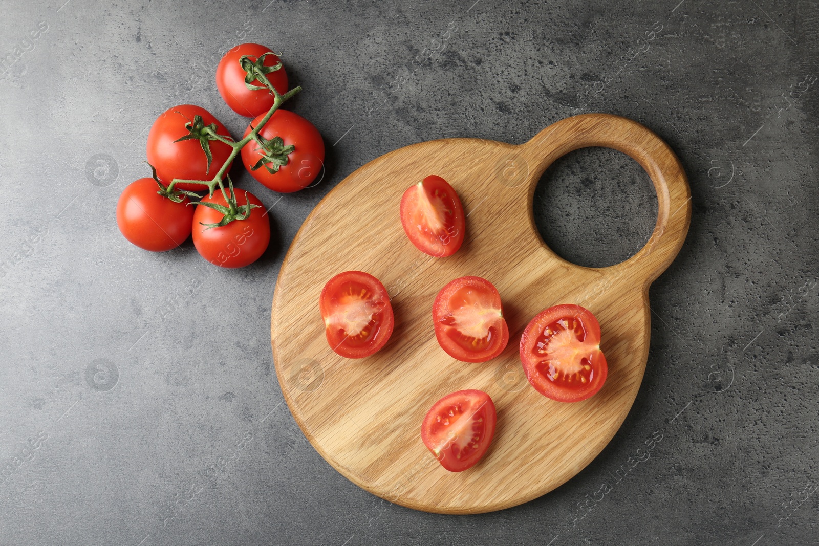 Photo of Cutting board with tomatoes on grey table, top view